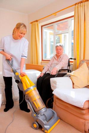 young Nurse cleaning for senior woman in a care home